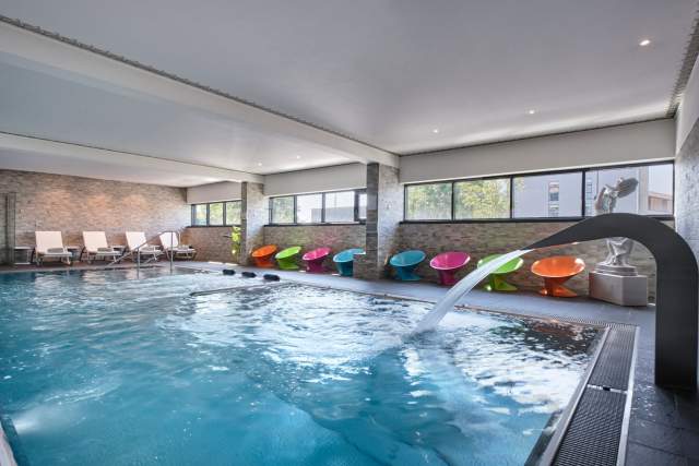 Indoor pool with colorful loungers at Hôtel Athena Spa in Strasbourg