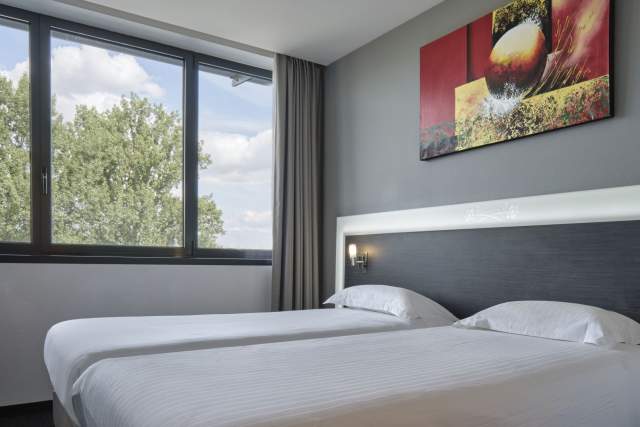 Two single beds with window in a room at Hôtel Athena Spa in Strasbourg