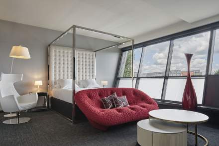 Suite avec lit à baldaquin et canapé rouge de l'Hôtel Athena Spa à Strasbourg