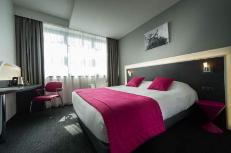 Chambre avec lit double et couvre-lit rose à l'Hôtel Athena Spa à Strasbourg