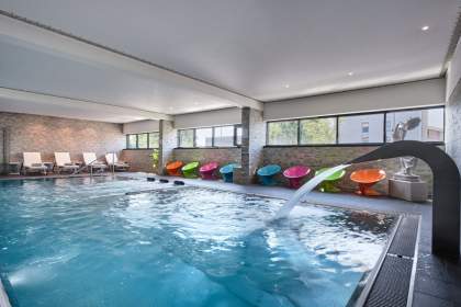 Piscine intérieure avec chaises colorés de l'Hôtel Athena Spa à Strasbourg